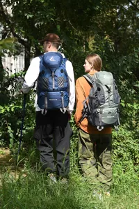 Couple wearing 50L outdoor adventure backpacks while hiking in a lush green forest
