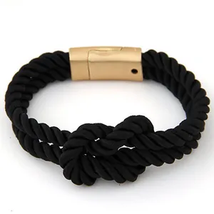 Détail d'un bracelet en corde tressée noire avec fermoir magnétique doré et nœud