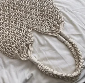 Close-up detail of the comfortable hand-woven braided handle on a white cotton rope bag