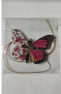 Macro view of the acrylic butterfly cross pendant inside its clear protective packaging.