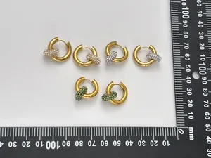 Nahaufnahme von Edelstahl-Goldreifen-Ohrringen mit CZ-Anhängern auf dem Messlineal