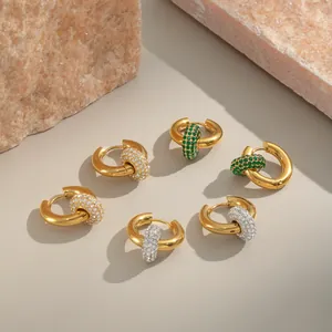 Nahaufnahme goldener Creolen mit abnehmbaren Anhängern aus grünen und weißen Steinen.