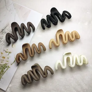 Top-down view of six wavy hair claw clips in various matte neutral earth tones.