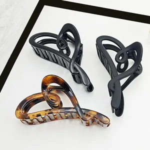 Detailed view of three elegant heart-shaped hair claw clips in tortoiseshell and black finishes.