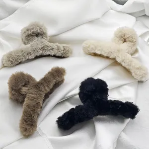 Soft faux fur hair claw clips in four neutral colors displayed on white silk fabric