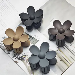 Close-up of four matte flower-shaped hair claw clips in various neutral colors