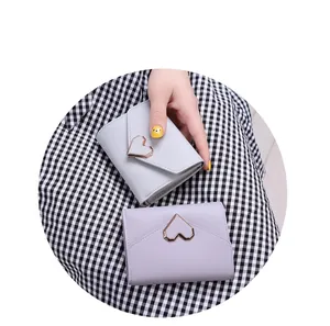 Close-up of heart buckle trifold wallets in grey and purple on checkered cloth.
