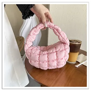 Detailed view of pink quilted mini cloud handbag featuring puffy texture and top handle