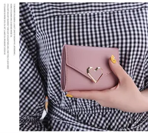Close-up detail of retro pink tri-fold wallet for women with gold heart metal buckle