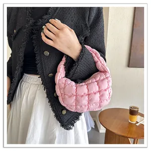 Close-up of a pink quilted cloud bag held by a model wearing a black tweed jacket