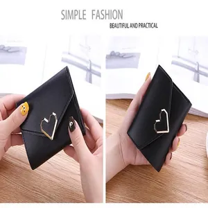 Close-up of a black tri-fold wallet featuring a gold heart-shaped metal clasp.