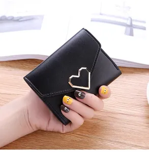 Detail shot of a black tri-fold women's wallet with an elegant gold heart buckle.
