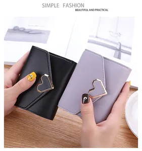 Close-up view of black and purple tri-fold lady wallets with gold heart-shaped buckles