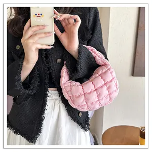 Detailed view of a pink puffy quilted cloud bag held by a model in a stylish outfit.