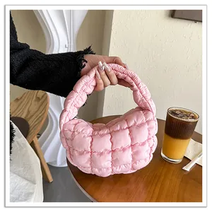 Close-up of pink quilted puffy mini cloud handbag in a lifestyle cafe setting