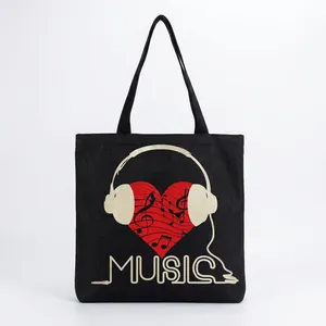 Close-up of artistic red heart and headphone music print on black canvas tote bag