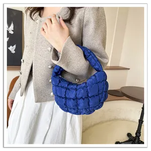 Stylish electric blue quilted puffy cloud bag held by a model in a trendy tweed jacket