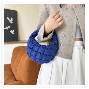 Detailed view of the stylish blue quilted cloud handbag being held by a fashion model.