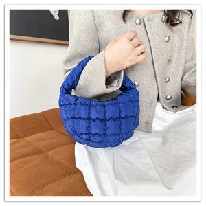 Detail view of blue quilted puffy handbag featuring soft down cotton filling texture.