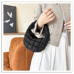 Detail view of a black quilted mini cloud bag held by a model in a chic fashion outfit