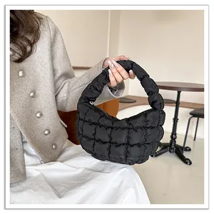 Detailed view of black quilted cloud bag featuring puffy texture and a stylish crescent shape