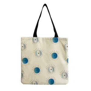 Close-up detail of a linen tote bag featuring a modern blue and white evil eye pattern print