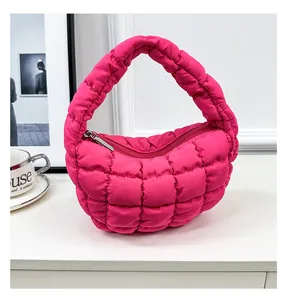 Detail view of a vibrant hot pink quilted puffer cloud bag resting on a white surface