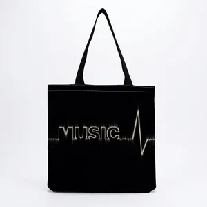 Detailed view of the black canvas tote bag featuring a white music heartbeat print