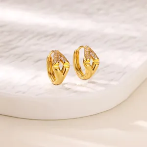 Primo piano di orecchini a cerchio placcati oro con pavé di zirconi a forma di V.