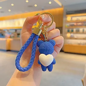 Close-up of a blue woven heart bear keychain with a braided strap and gold ring