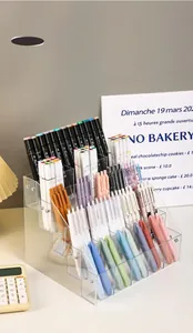 Tiered clear acrylic organizer filled with various colorful pens on a desk