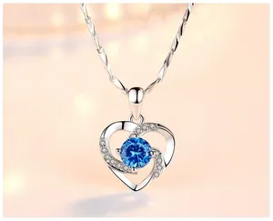 Gros plan détaillé d'un pendentif en forme de cœur en argent avec un zircon bleu central