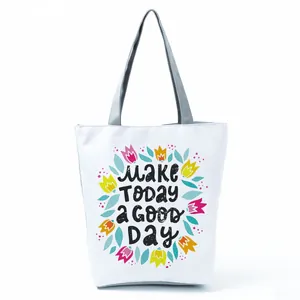 Close-up of a white tote bag with colorful flower patterns and positive English text