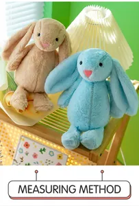 Close-up of cute beige and blue long-eared bunny plush toys on a shelf