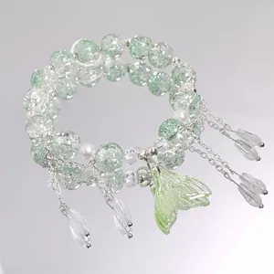 Detailed view of a light green beaded bracelet with a mermaid tail pendant and charms.