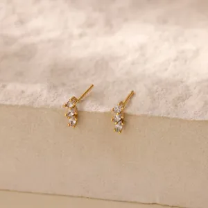 Primo piano di eleganti orecchini a lobo d'oro con tre pietre di zircone marquise brillanti