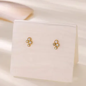Primo piano di eleganti orecchini a lobo dorati con un design a grappolo di quattro cristalli.