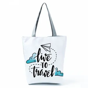 White canvas tote bag with 'Live to Travel' print and paper plane cartoon graphic