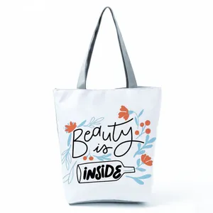 Close-up of white tote bag featuring floral illustration and Beauty is INSIDE slogan