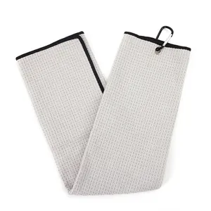 Close-up of grey waffle weave golf towel with metal grommet and black carabiner clip.