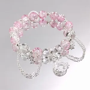 Pink crystal beaded bracelet with silver moon and star charms on a mirror surface