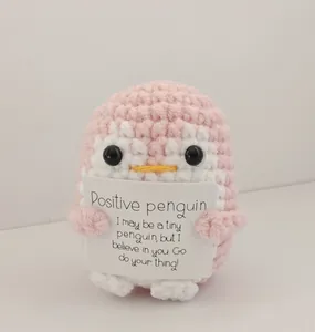 Handmade pink crochet penguin amigurumi plush toy holding an inspirational card