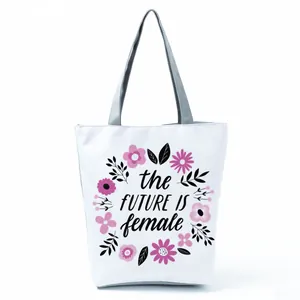 Close-up detail of the floral print and slogan on this white canvas shoulder tote bag