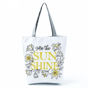 Detailed view of a white canvas tote bag featuring floral Be the Sun Shine print design