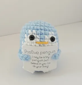 Detailed shot of a light blue handmade crochet penguin with an encouraging card