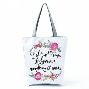 Detailed view showing the floral wreath and English quote print on a white tote bag