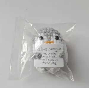 Close-up detail of handmade crochet positive penguin plush toy in clear packaging bag