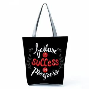 Detail view of black tote bag with 'Failure is Success' inspirational quote print