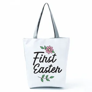 Detail view of a white tote bag featuring a 'First Easter' floral print with gray straps.
