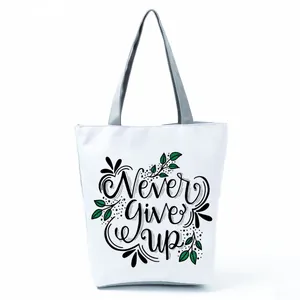 White canvas tote bag featuring decorative 'Never Give Up' letter print and leaves